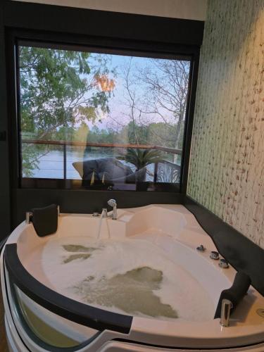 a bath tub in a bathroom with a large window at Hoota Cottage Bojana River in Ulcinj