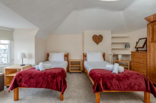 a bedroom with two beds with red sheets at Church View - Elie in Elie