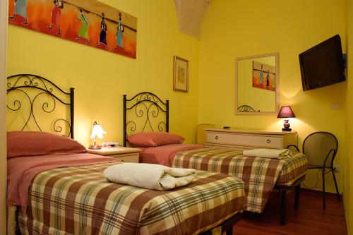 2 camas en una habitación con paredes amarillas en B&B La Corte Lecce, en Lecce
