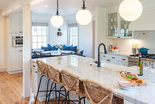 a kitchen with white cabinets and a large island with bar stools at Luxurious Nantucket Getaway Heated Pool in Nantucket