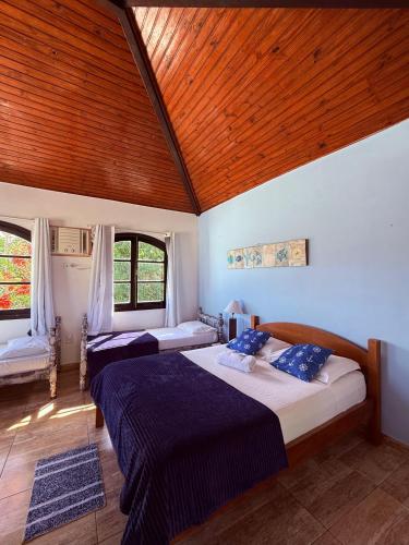 a bedroom with two beds and a wooden ceiling at Pousada bella mar buzios in Búzios