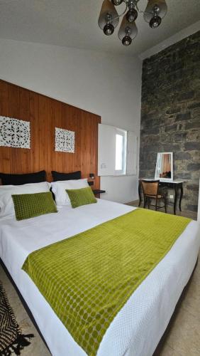 a bedroom with a large bed with a green blanket on it at Quinta das Candeias in Candelária