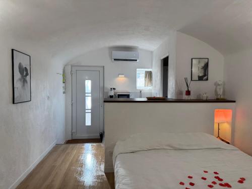 a white bedroom with a bed and a kitchen at "L'écrin d'amour" - Suite, Spa & Double pommeau in Ville-sous-Anjou