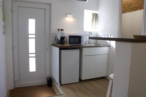 a white kitchen with a counter and a door at "L'écrin d'amour" - Suite, Spa & Double pommeau in Ville-sous-Anjou