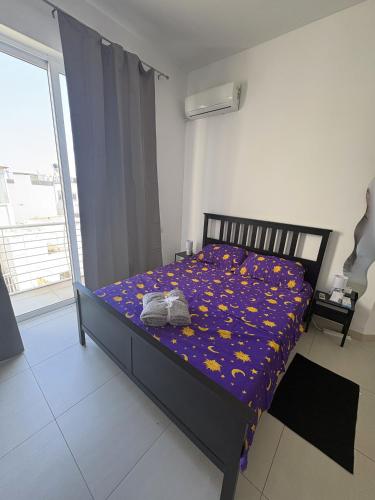 a bedroom with a bed with a purple blanket with yellow flowers at Grand Residence 3-Bedroom Spacious Premium Central Apartment in Is-Swieqi