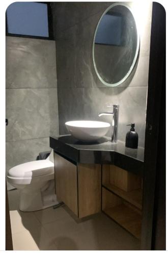 a bathroom with a sink and a toilet and a mirror at Complejo Las Flores departamento 3 in Durango