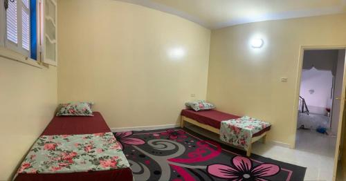 a small room with two beds and a rug at Maison yassine in Douz