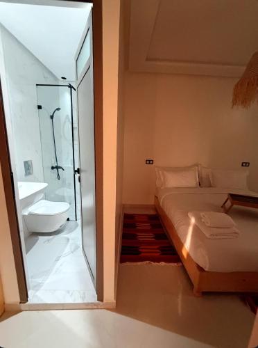 a bathroom with a shower and a bed and a sink at Swellora Surf Camp Imsouane in Imsouane
