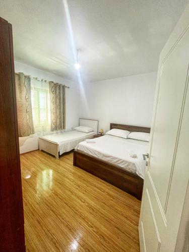 sypialnia z dwoma łóżkami, oknem i drzwiami w obiekcie OLIVE Home w Durrës