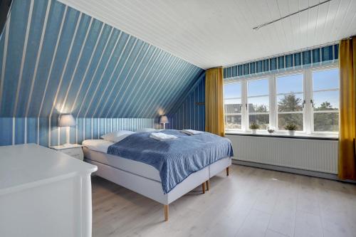a bedroom with a bed and a blue striped wall at Klithuset in Henne Strand