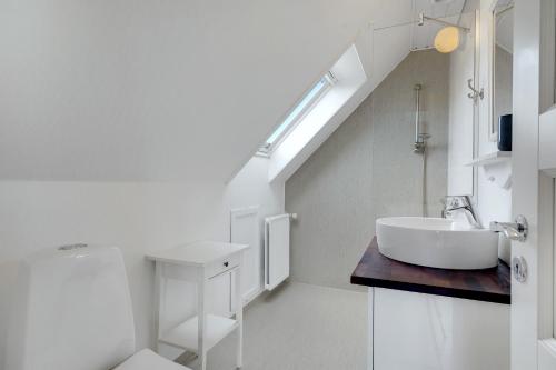 a white bathroom with a sink and a staircase at Klithuset in Henne Strand