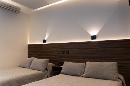 two beds in a room with two lights on the wall at Hotel Melanie Tepic in Tepic