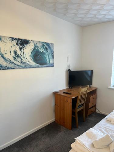 a bedroom with a desk and a tv and a wave on the wall at Serene Property Next to Southampton General Hospital in Southampton