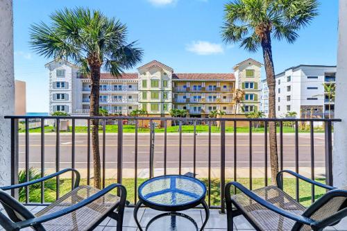 a patio with chairs and a table and palm trees at Madeira Place 205 in St. Pete Beach