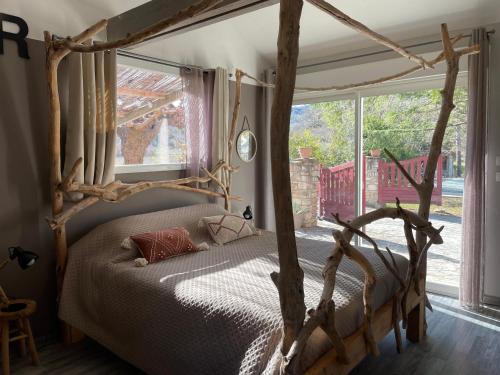 a bedroom with a wooden canopy bed and a window at Le petit cabanon in Lagorce