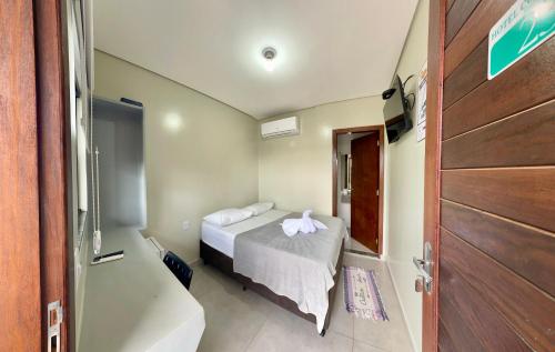 a small room with a bed and a door at Hotel Colina Verde in Lucas do Rio Verde