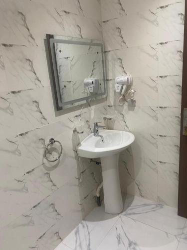 a white bathroom with a sink and a mirror at Apparthotel Le SALY Beach yenne in Toubab Dialaw