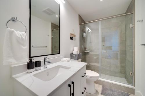 a white bathroom with a sink and a shower at Modern Penthouse in Central KW in Kitchener
