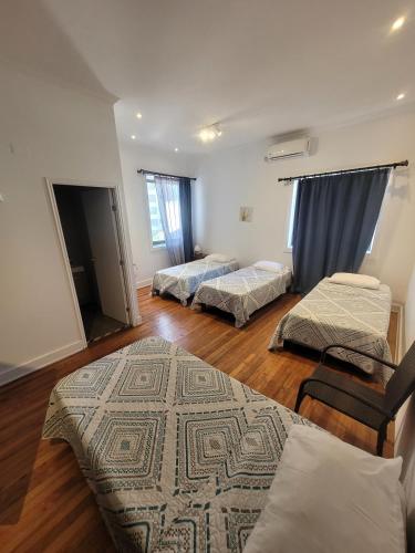 a room with three beds and a rug on the floor at Hotel Traslaviña in Viña del Mar