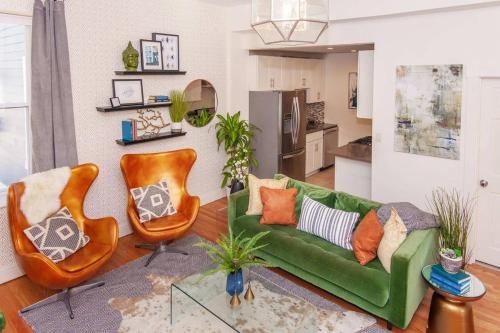 a living room with a green couch and two chairs at Cozy Duplex Near T in Boston