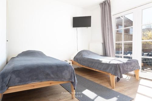 a bedroom with two beds and a tv and a window at Monteurunterkunft Kuddel in Laboe