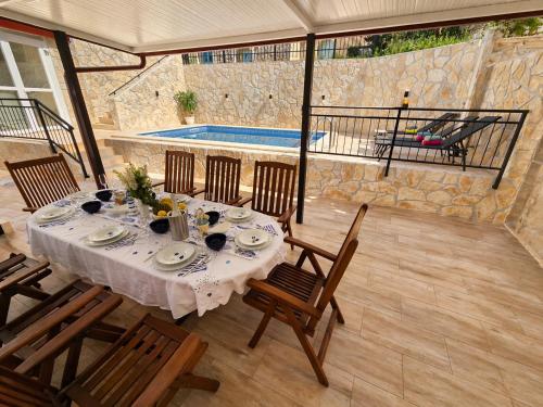 a dining table and chairs in a patio with a pool at Adria Stone House in Grižane