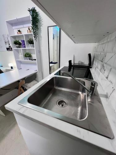 a stainless steel sink in a white kitchen at Mini-studio de 15m2 à 8 min de Paris in Maisons-Alfort
