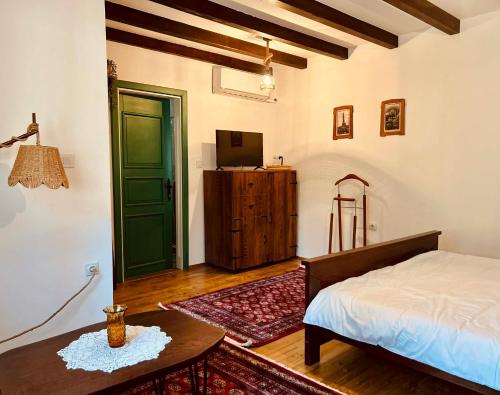 a bedroom with a bed and a table and a green door at Selsko domacinstvo Nevena in Kumanovo