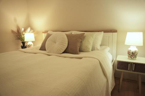 a bedroom with a white bed with two lamps at Vintage Apartman Gyula in Gyula