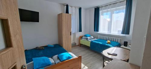 a small room with two beds and a tv at Magma Grzybowo in Grzybowo