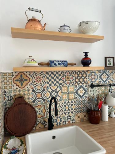 a kitchen with a sink and tiles on the wall at Backyard Cottage in Răhău