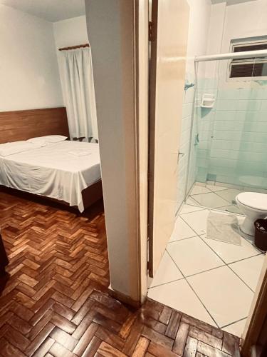 a bathroom with a bed and a shower and a toilet at Hotel América in Ivaiporã