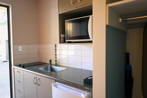 a kitchen with a sink and a microwave at La Rochelle Motel in Akaroa