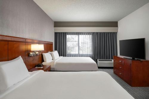 a hotel room with two beds and a flat screen tv at Courtyard by Marriott Albuquerque Airport in Albuquerque