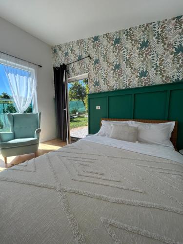 a bedroom with a large bed and a green headboard at Backyard Cottage in Răhău