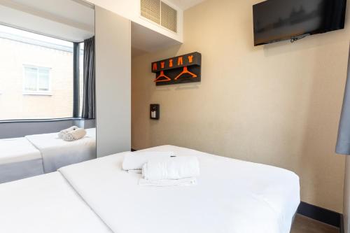 two beds in a room with a tv on the wall at easyHotel Liverpool in Liverpool
