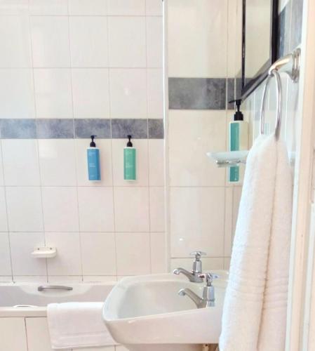 a white bathroom with a sink and a tub at Durban Oceanic Apartment 82B in Durban