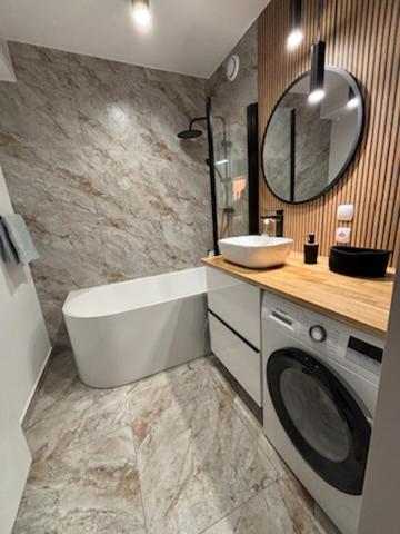 a bathroom with a tub and a sink and a washing machine at Pod Daglezją in Łagów