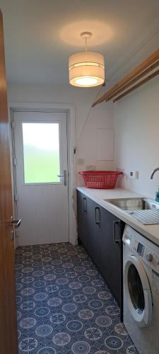 a kitchen with a washing machine and a window at Solheim Self Catering in Whiteness