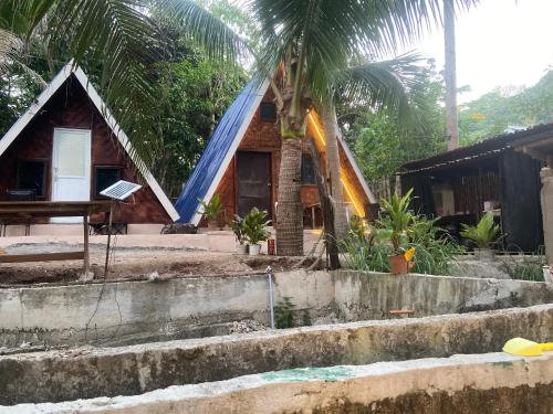 a house with a blue roof and some palm trees at Sea Breeze Lodge in Siquijor