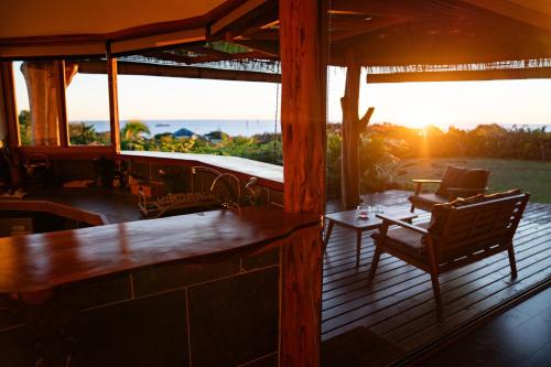 a porch with a table and chairs and the sunset at Kona Koa Lodge in Hanga Roa