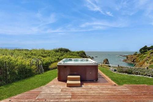 a hot tub sitting on a patio near the ocean at Luxe Remodeled Oceanfront Home on the Bluff in Mendocino