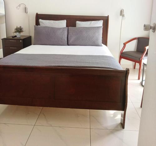 a bedroom with a bed with a wooden frame and a chair at Durban Oceanic Apartment 82B in Durban