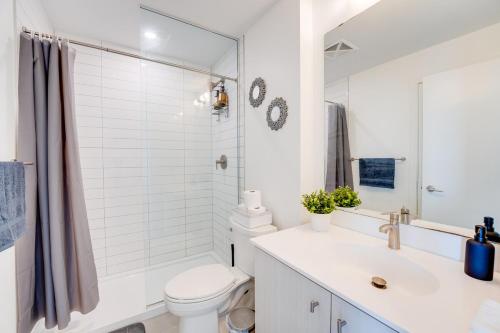 a white bathroom with a toilet and a sink at Stylish Open Concept Condo with Gym in Kitchener