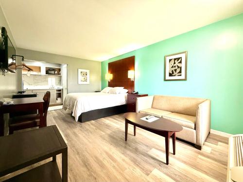 a hotel room with a bed and a couch and a table at Americas Best Value Inn Suites & Studios Blytheville by Sonesta in Blytheville