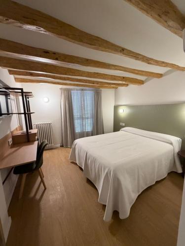 a bedroom with a large white bed and a desk at Hotel Tall de Conill in Capellades