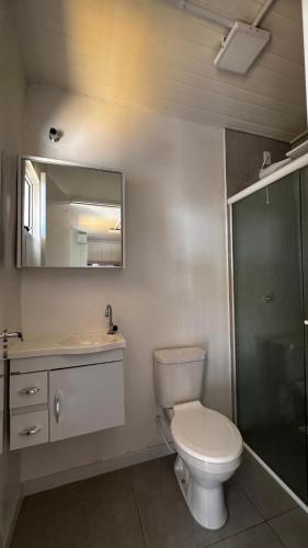 a bathroom with a toilet and a sink and a mirror at Pousada Fornerolli in Penha