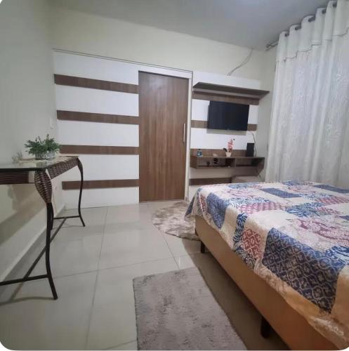 a bedroom with a bed and a desk and a television at Refúgio Aconchego in Sorocaba