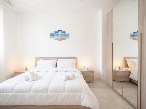 a bedroom with a large white bed and a mirror at SPA & RELAX Aesthetic Apartment 50m dal mare in Monopoli