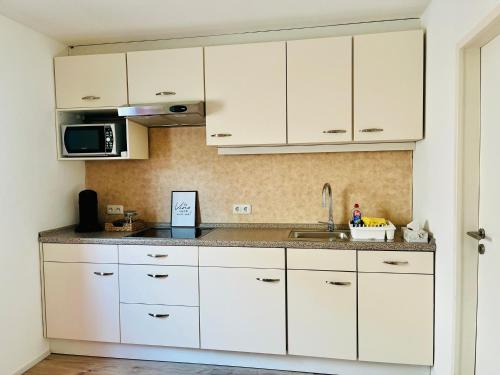 a kitchen with white cabinets and a sink at Ferienwohnung Moselverliebt in Schweich